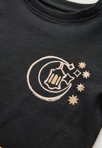 Schwarzes Baumwoll-T-Shirt mit einem cremefarbenen Grafikdesign eines Halbmonds, einer Laterne und Sternen, mit glatter Textur und rundem Ausschnitt.