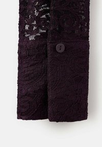 Tejido de encaje púrpura oscuro con patrones florales, que presenta un cierre de botón en el puño. El material tiene una apariencia texturada y delicada.