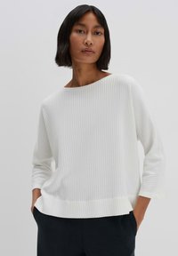 White ribbed sweater with a wide neckline, three-quarter sleeves, and a relaxed fit. Fabric has a textured pattern.