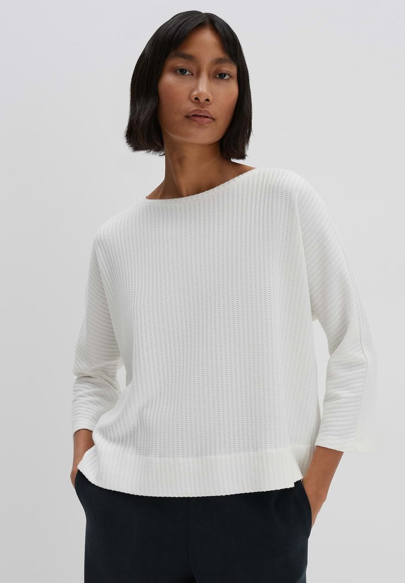 White ribbed sweater with a wide neckline, three-quarter sleeves, and a relaxed fit. Fabric has a textured pattern.