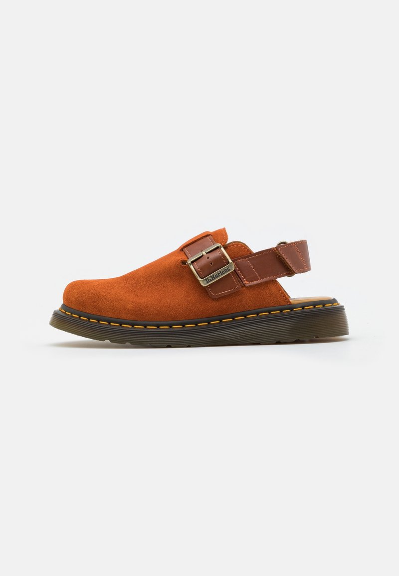 Chaussure homme en daim orange à enfiler, avec une sangle ajustable en cuir marron et une boucle, semelle épaisse noire avec couture jaune.