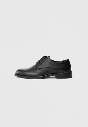 Schwarze Lederschuhe mit glattem Zehenbereich und strukturierten Seitenpaneelen, fünf Ösen und einer flachen Gummisohle.