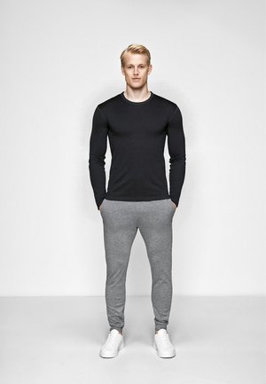 Sort langærmet skjorte og grå sweatpants lavet af blødt stof, suppleret med hvide sneakers; afslappet, tætsiddende design med en simpel æstetik.