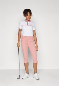 Golfový outfit pozostáva z bieleho polokošele s ružovým golierom a akcentmi, doplnený o ružové krátke nohavice. Príslušenstvo zahrnuje golfovú palicu.