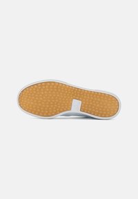 Vit sneakersula med ett texturerat gummimönster. Har en slät vit kant och en liten logotyp. Tjock och vadderad design.