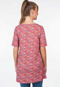 Blumen-Tunika in Rot mit rosa und grauen Akzenten. Kurze Ärmel, runder Ausschnitt und ein leicht verlängertes hinteres Saum. Weicher Stofftextur.