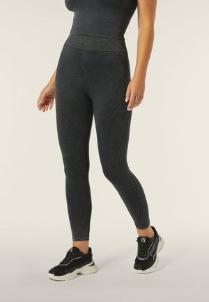 Leggings neri a vita alta con vita a coste, tessuto testurizzato e cuciture a contrasto, abbinati a sneakers nere con suole bianche.