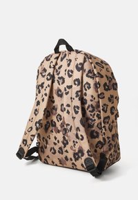 Leopard print backpack in beige and black, featuring fabric material, adjustable straps, and a top handle for easy carrying.