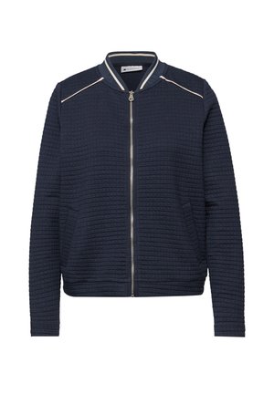 Veste bomber matelassée bleu marine avec fermeture éclair argentée, poches latérales et accents de bandes blanches sur le col et les épaules.