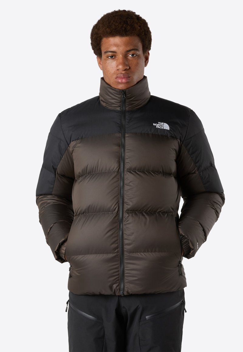 Dunkelbraune und schwarze Daunenjacke mit hohem Kragen, Frontreißverschluss und Logo auf der Brust; dicke Nähte und gepolstertes Design für Wärme.