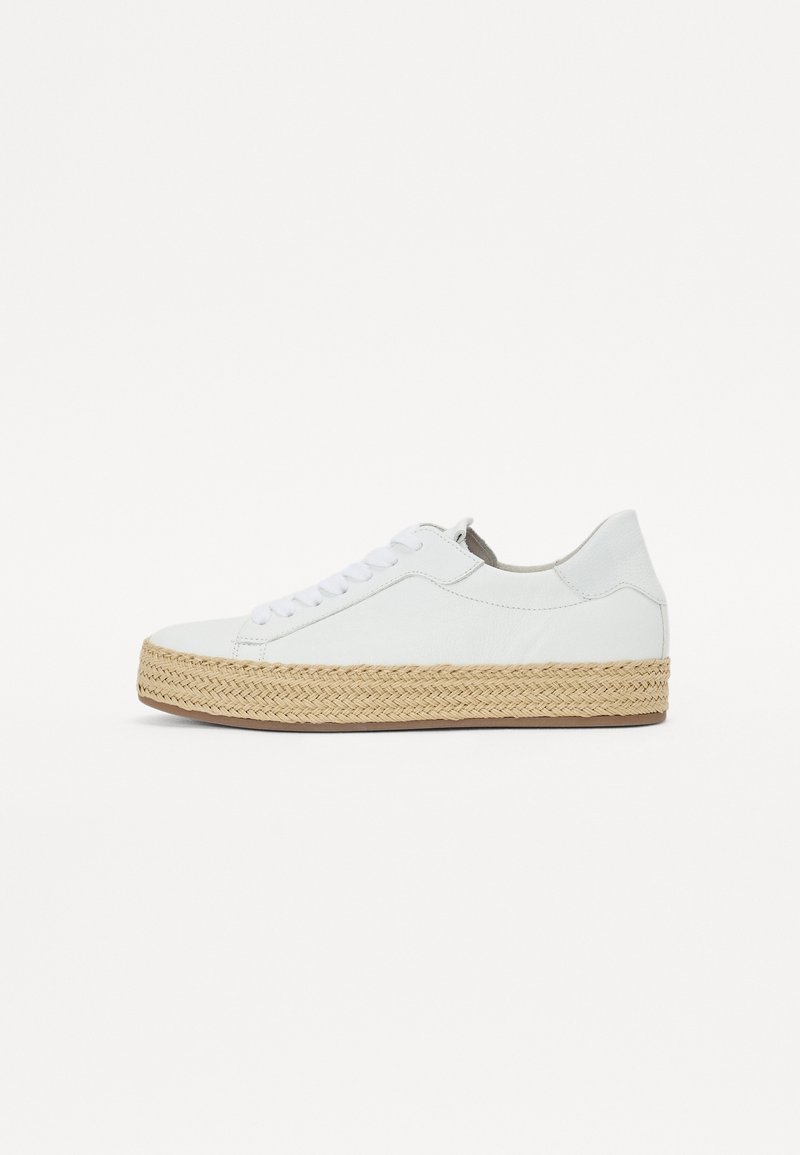 Sneakers basses blanches avec des lacets blancs et une épaisse semelle en corde tissée beige sur un fond blanc uni.