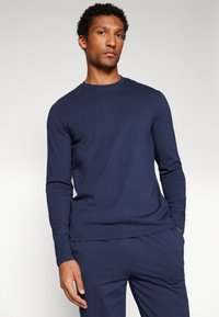 Navy long-sleeve t-shirt in soft fabric with a crew neckline. Features a straight hem and fitted sleeves. Paired with matching pants.