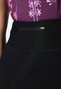 Zwarte hooggewaisted rok met een gladde textuur, voorzien van minimale stiksels, een strak ontwerp en een kleine zwarte hardware-accentuering in de taille.