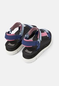 Flerfärgade sandaler med blå, rosa och svarta remmar; texturerad sula med prickar; dämpad fotbädd; justerbara stängningar.