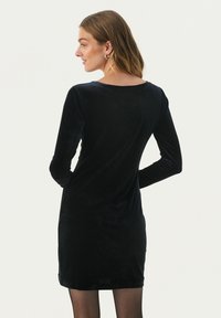 Rochie din catifea neagră cu mâneci lungi, guler rotund, design ajustat și lungime mini. Textură netedă cu o strălucire subtilă, potrivită pentru ocazii formale.