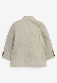 Chaqueta de lino beige claro con cuello estructurado, mangas tres cuartos y adornos de botones en los puños. Presenta una abertura en la parte posterior y un diseño sencillo.