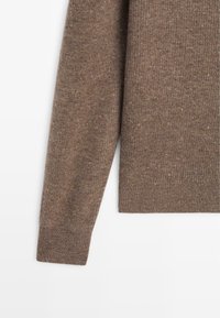 Brązowy dziany sweter o teksturowanym wykończeniu, z prążkowanymi mankietami i ściągaczem. Charakterystyczne cętki dodają tkaninie wizualnego uroku.