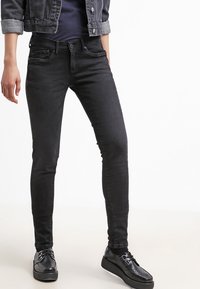 Czarne obcisłe dżinsy wykonane z denimu, z klasycznym pięciopocketowym designem, zapięciem na guzik z przodu oraz minimalistycznymi detalami szwów.