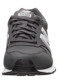 Svart atletisk sko med övre del av nät och syntetmaterial, med grå logotyp, texturerade skosnören och vit sula. Rundad tå och dämpad design.