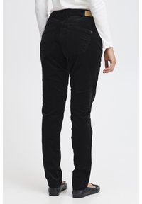 Fekete kordbársony nadrág karcsúsított szabással, két hátsó zsebbel és közép magasított derékkal. Az anyag texturált megjelenést és érzetet biztosít.