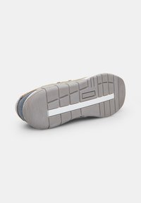 Talpa de pantof sport din cauciuc gri, cu o suprafață texturată, caneluri flexibile și o bandă albă de accent. Design durabil și cu model.