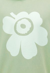 Ανοιχτό πράσινο φούτερ με μεγάλο λευκό γραφικό λουλούδι που έχει κεντρικό κυκλικό σχέδιο και στρογγυλά πέταλα, με ομαλή υφή.