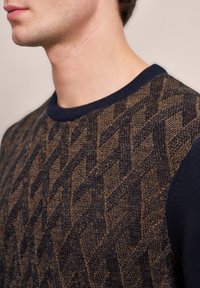 Strickpullover mit einem geometrischen Muster in Braun und Dunkelblau. Verfügt über einen Rundhalsausschnitt und einen strukturierten Stoff am Körper, glatte Ärmel.