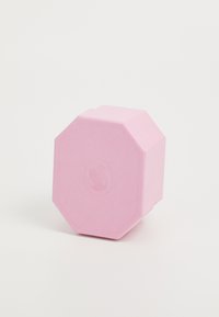 Octagonal pink box made of textured material, featuring an embossed logo on one side. Minimal design, soft color with no additional accents.