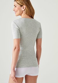 Top gris de manga corta con un diseño ajustado y una textura sutil, combinado con pantalones cortos blancos. Presenta un escote redondo y una tela suave.