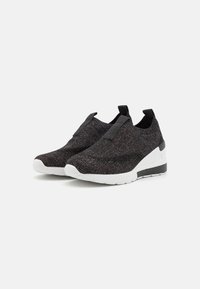 Svarta slip-on sneakers med stickad textur, elastiska sidopaneler och en kraftig vit sula med svarta detaljer vid hälen.