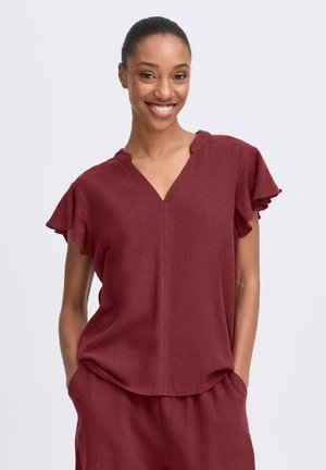 Bordeauxkleurige blouse met korte mouwen, een V-hals en schouderpuffen. Gemaakt van zachte stof, met een ontspannen pasvorm en zijzakken in de bijpassende broek.