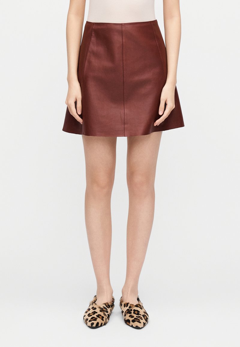 Bourgognefarvet lædernederdel i miniformat med en udvidet form og en glat tekstur. Stylet med leopardprint slip-on sko.