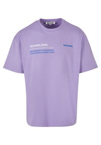 Lavender cotton t-shirt with short sleeves, featuring printed text in white and blue: "TECHNOLOGIC." and "THIS PROPERTY IS PROTECTED BY ELECTRONIC SURVEILLANCE."