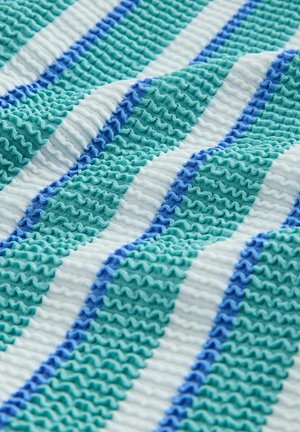 Texturált szövet, váltakozó türkiz, világoskék és fehér csíkokkal, hullámzó mintákkal, hangsúlyozva a rétegzett, fodrozódó megjelenést.