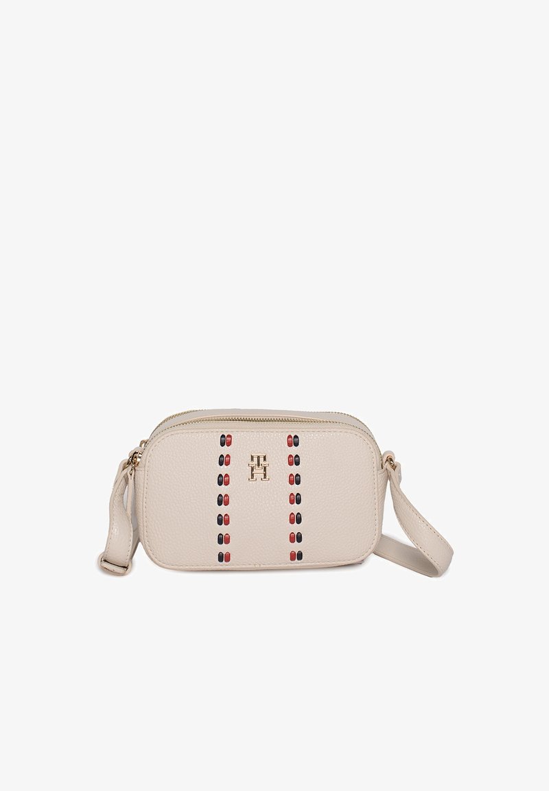 Beige leren crossbodytas met gouden rits, rood-zwart kralenornament en gouden "TH"-logo aan de voorkant.