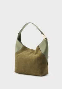 Olivzaļa zamšādas un ādas plecu soma ar plašu siksnu un zelta toņa detaļām uz balta fona.