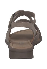 Bruine sandaal met meerdere smalle banden en een gevoerd voetbed. De zool is plat met een kleine hak. Textuuraccent op de band.