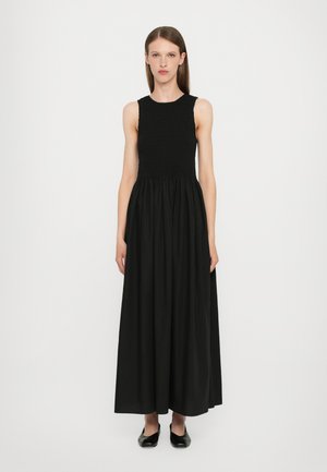 Robe maxi noire avec un corsage ajusté et smocké, et une jupe fluide. Fabriquée en tissu léger, avec un col rond et sans manches.