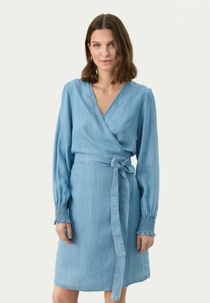 Light blue denim wrap dress with long sleeves, smocked cuffs, and a tie belt at the waist. V-neck design and smooth texture.