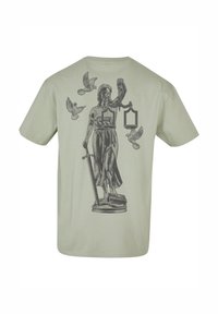 Lys grøn bomulds t-shirt med et sort trykt grafisk billede af en statue, der holder vægte og et sværd, omgivet af flyvende fugle.