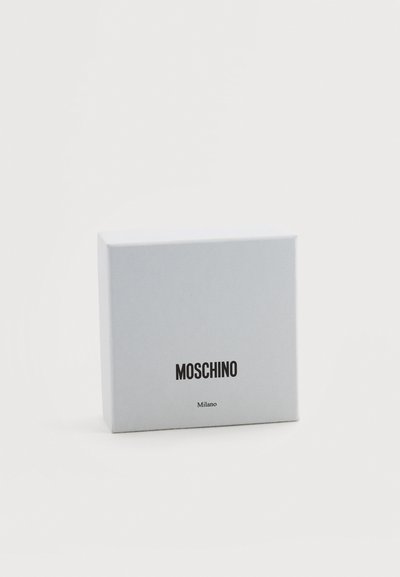 Boîte rectangulaire blanche de marque Moschino Milano sur un fond blanc uni, légèrement inclinée.