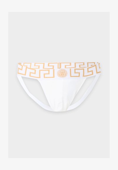 Slip bikini blanc pour homme avec un motif clé grec doré et un logo tête de Méduse sur la ceinture, sur un fond uni.