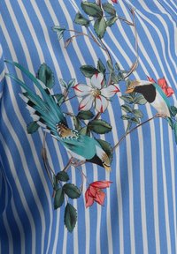 Tissu rayé vertical bleu et blanc avec des oiseaux turquoise imprimés, des feuilles vertes et des fleurs blanches et roses.