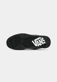 Suola di scarpa nera in gomma con modelli di presa testurizzati; presenta un prominente logo "VANS" bianco. Forma piatta e arrotondata con bordi spessi e scanalature.