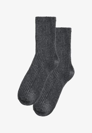 Paar dunkelgraue, gerippte Stricksocken mit mittlerer Wadenlänge, die Fersen- und Zehenbereiche deutlich auf weißem Hintergrund zeigen.