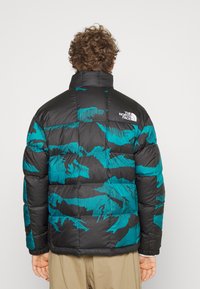 Giubbotto imbottito nero con motivo camouflage teal, caratterizzato da un colletto alto, polsini elastici e dettagli con logo sulla parte superiore della schiena.