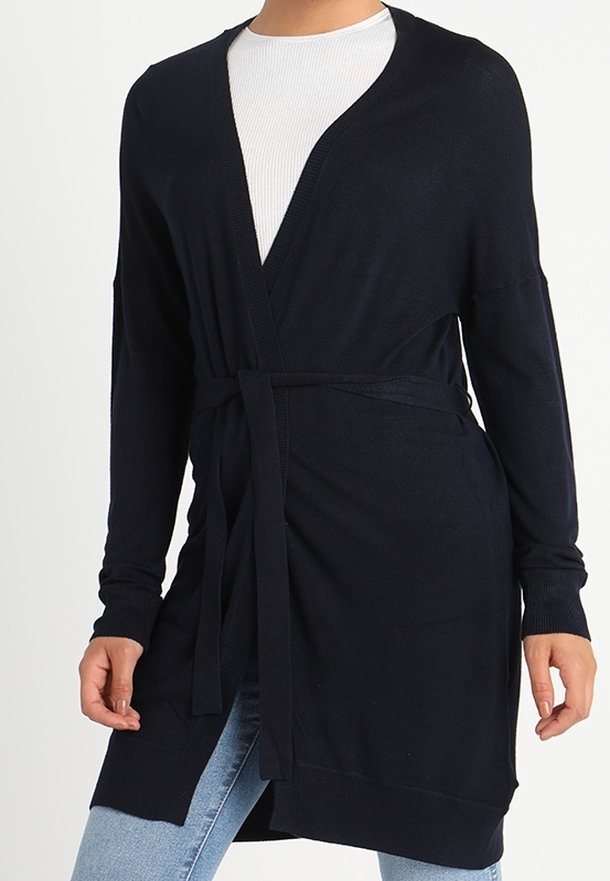 Granatowy długi kardigan z dekoltem w serek, długimi rękawami, paskiem do związania i otwartymi bokami, wykonany z miękkiego, lekkiego materiału. Posiada prążkowane mankiety.