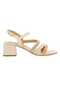 Sandale beige avec un talon bloc, présentant trois courroies tressées décorées de perles. Fermeture par boucle sur la lanière de la cheville.