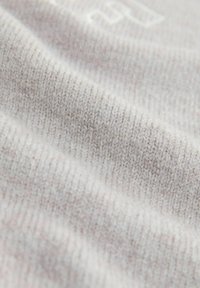 Tessuto lavorato a maglia grigio chiaro con una superficie morbida, caratterizzato da un motivo sottile e fili intrecciati. Finitura liscia con un leggero lucido.
