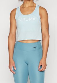 Jasnoniebieski krótki top na ramiączkach z białym logo "PUMA", zestawiony z dopasowanymi niebieskimi legginsami o wysokim stanie z małym czarnym logo.